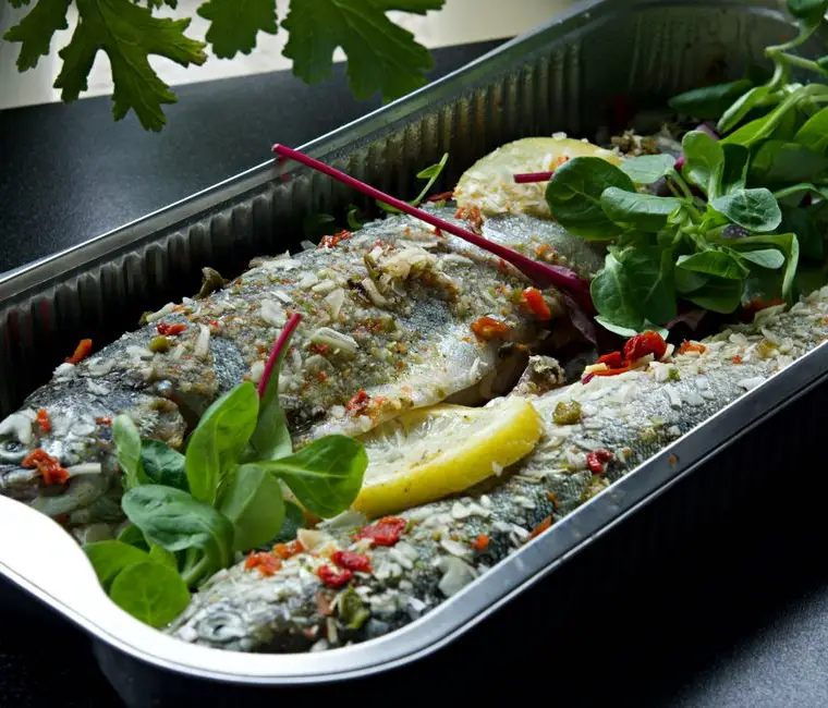Poisson entier cuit au four, peau dorée, sur un plat